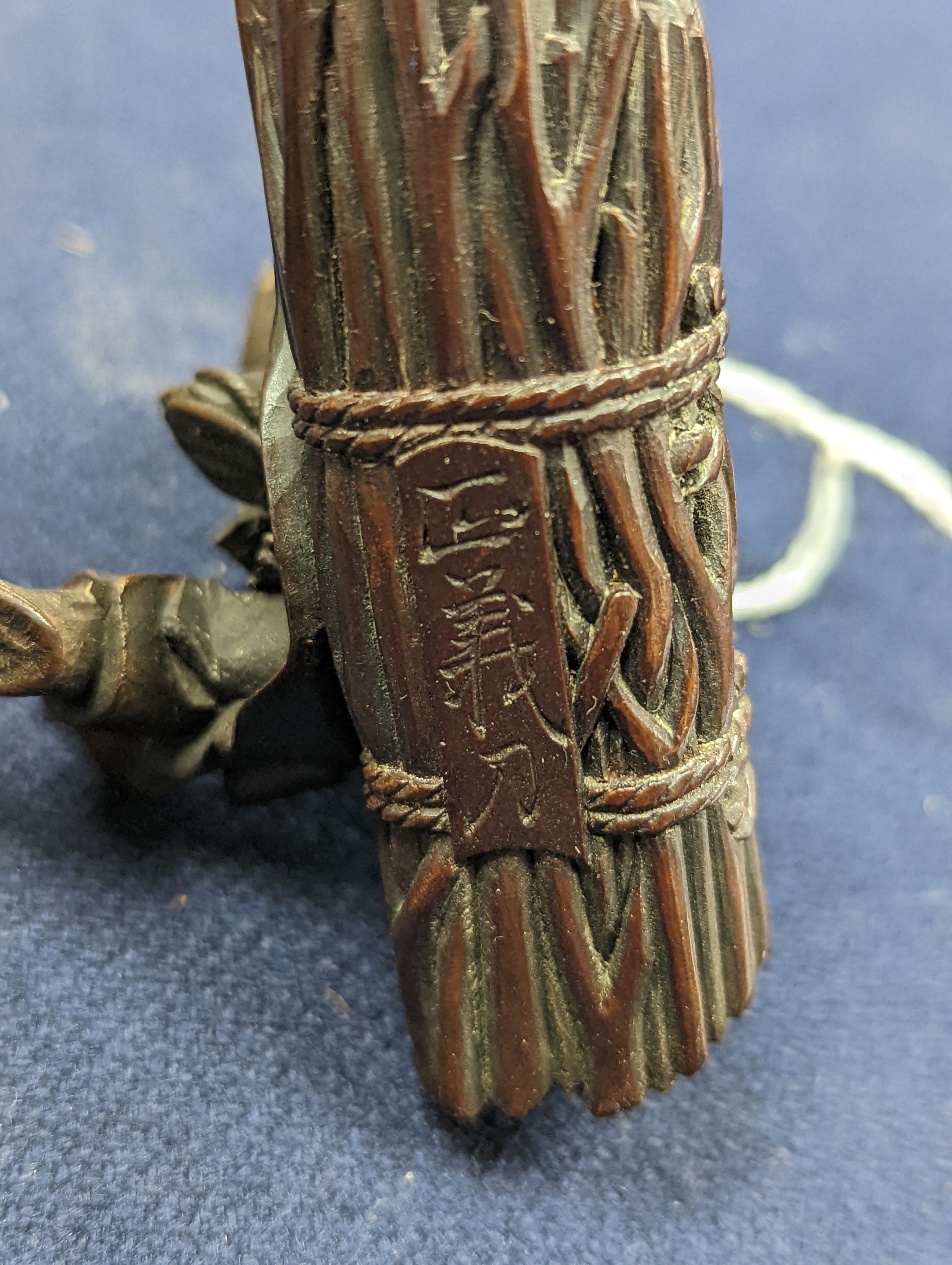 A 19th century Japanese wood okimono of a seated man smoking a pipe, signed, 7.8cm on a later hardwood stand